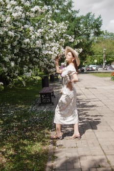 An attractive long-haired woman walks in the spring in the park of blooming apple trees. Spring portrait of a woman