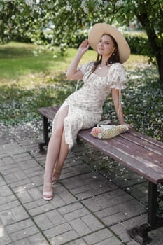 An attractive long-haired woman walks in the spring in the park of blooming apple trees. Spring portrait of a woman