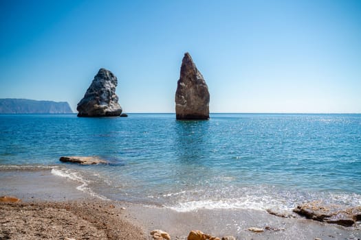 Two rocks stick out of the water in the middle of the turquoise sea. Scenic ocean views. High quality photo. Like in Iceland.