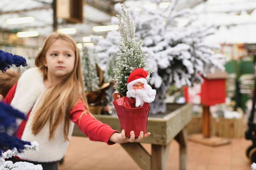 Girl holding an artificial Christmas tree with Santa Claus in her hands