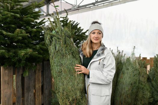 A woman buying a Christmas tree in the market.