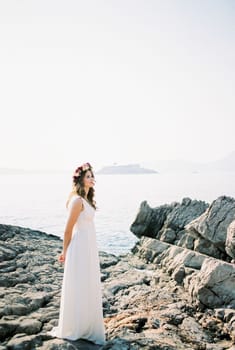 Bride stands on a rocky seashore and looks into the distance. High quality photo