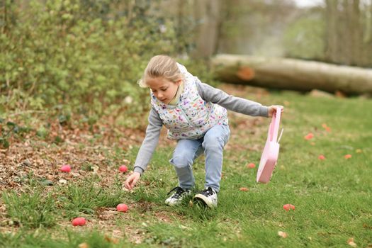 Girl collects the eggs in a basket Easter