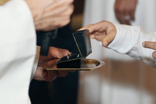 The priest in the church passes the wedding rings