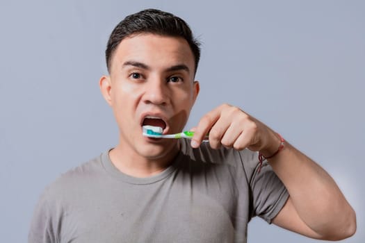 Handsome guy brushing his teeth isolated, Close up of handsome man brushing his teeth. Brushing and dental hygiene concept. Close up of people brushing their teeth on isolated background