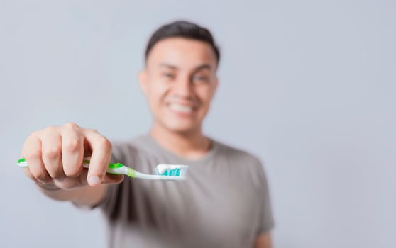 Smiling young man showing toothbrush with toothpaste isolated. Smiling people holding toothbrush with toothpaste with copy space, Smiling man showing a toothbrush in the foreground