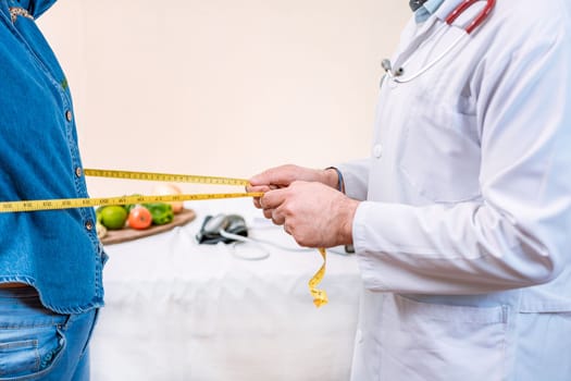 Hands of nutritionist measuring waist to female patient. Concept of weight loss and professional nutritionist, Close up of nutritionist measuring waist to female client. 