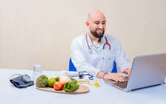 Nutritionist doctor using laptop at workplace. Bearded nutritionist doctor working on laptop at desk, Smiling nutritionist with laptop at desk