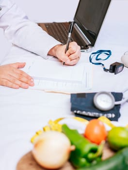 Hands of male nutritionist taking notes at his desk, Nutritionist hands taking medical records in the office. Close-up of nutritionist writing on notepad