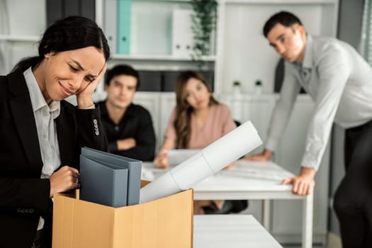 An emotional image of a fired employee packing up her possessions for not being competent. Feeling overwhelmed and embarrassed in front of her coworkers.