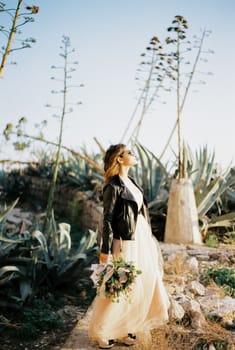 Bride in sunglasses stands on a stone path and looks at the sun. High quality photo
