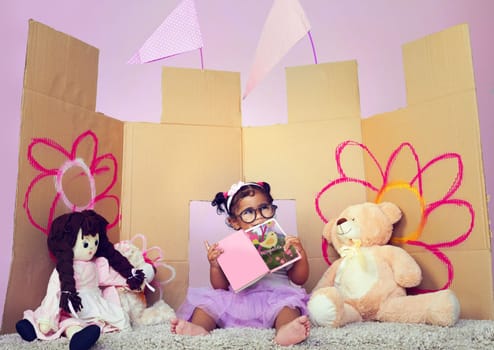 Dream big baby girl. an adorable little girl reading a book surrounded by her toys