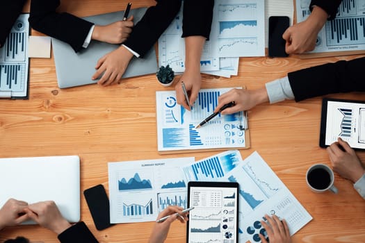 Top-view closeup business team of financial data analysis meeting with business intelligence, report paper and dashboard on laptop. Business group people working together in harmony office.