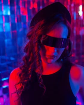 Close-up portrait of a caucasian woman in sunglasses in neon light against a mirror wall