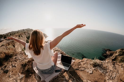 Woman sea laptop. Business woman in yellow hat working on laptop by sea. Close up on hands of pretty lady typing on computer outdoors summer day. Freelance, digital nomad, travel and holidays concept.