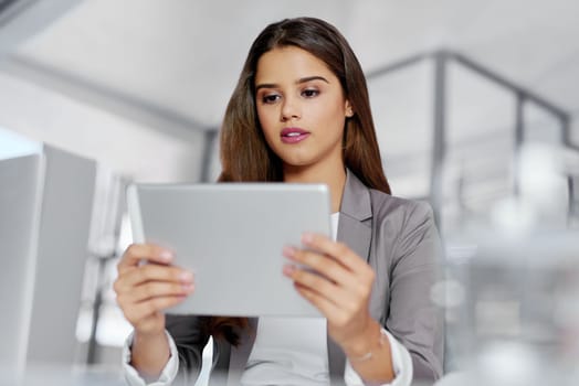 The tool to give her business an advantage. a young businesswoman working on a digital tablet in an office