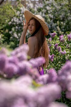 portrait of young woman with long hair outdoors in blooming lilac garden.