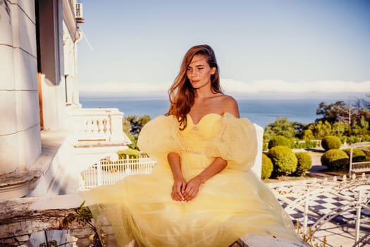 Woman yellow sea dress. Portrait of a beautiful young woman with brown hair in a gorgeous yellow dress looks into the distance