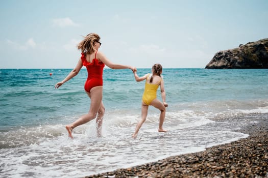 Happy loving family mother and daughter having fun together on the beach. Mum playing with her kid in holiday vacation next to the ocean - Family lifestyle and love concept.