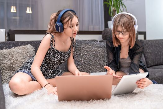 children have fun at home with modern technology, they use headphones and a laptop. High quality photo