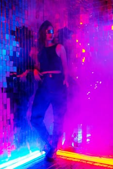 Portrait of a caucasian woman in sunglasses in neon light against a mirror wall