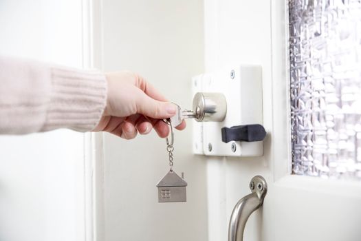 female hand putting house key into front door lock of house, Woman using a silver key to open lock of the front door , white wooden door open locked house, security and save copy space