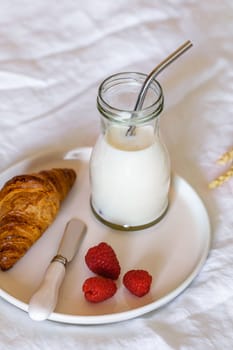 french breakfast on a bed, croissant, milk and fresh berries, copy space