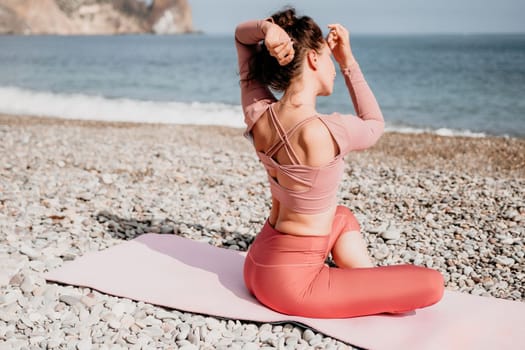 Young woman with long hair in white swimsuit and boho style braclets practicing outdoors on yoga mat by the sea on a sunset. Women's yoga fitness routine. Healthy lifestyle, harmony and meditation