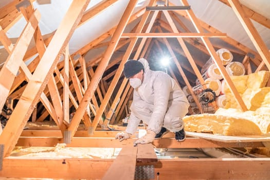 a man insulates the roof and ceiling of the house with glass wool