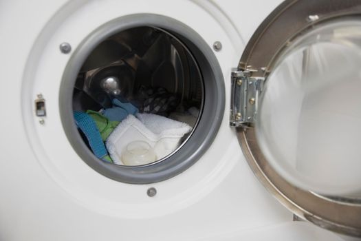Laundry concept. white and modern washing machine with open door standing inside bright apartment or house light interior close up housekeeping