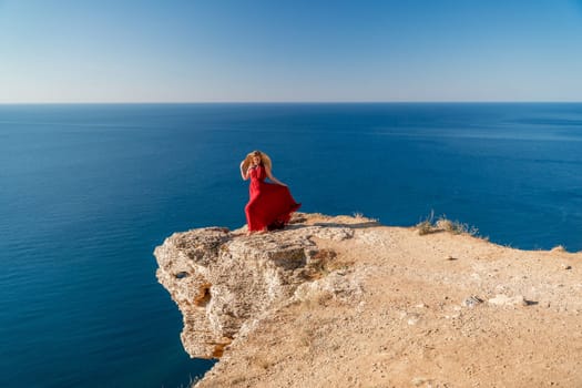 A woman in a red flying dress fluttering in the wind, against the backdrop of the sea