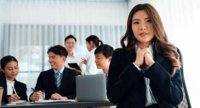 Focus portrait of female manger, businesswoman in the harmony meeting room with blurred of colleagues working together, analyzing financial paper report and dashboard data in background.