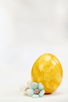 Easter eggs painted in pastel colors on a white background with copy space and cute spring flowers, Happy Easter Holiday concept with space for text. Yellow pink and blue bright colors