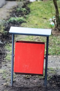 Red metal litter bin on the sidewalk close up