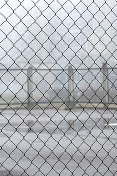 Fence net against the backdrop of a playground for games in the fog
