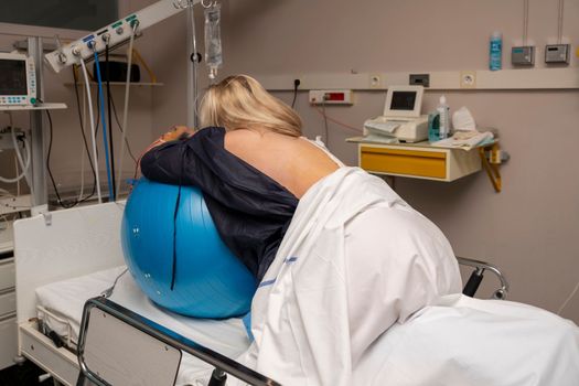 Woman during contractions on a blue fitness ball Parturition hospital