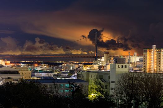 Low snow clouds over suspension bridge glow from city lights at night. High quality photo