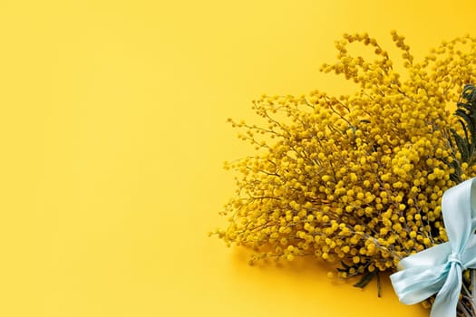 Frame of yellow mimosa flowers bouquet on yellow solid bakground. Spring concept. Flat lay. Top view, banner