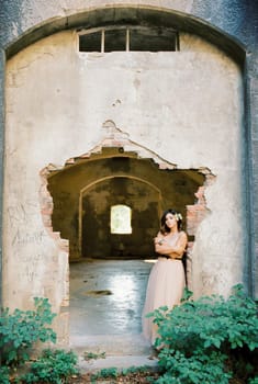 Bride stands leaning against the wall of an old stone fortress. High quality photo
