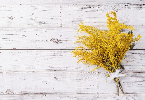 Frame of yellow mimosa flowers bouquet on wooden bakground. Spring concept. Flat lay. Top view, banner
