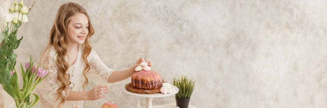 A girl with long hair in a light dress is sitting at the Easter table with cakes, spring flowers and quail eggs. Happy Easter celebration