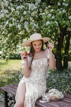 An attractive long-haired woman walks in the spring in the park of blooming apple trees. Spring portrait of a woman