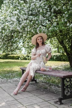 An attractive long-haired woman walks in the spring in the park of blooming apple trees. Spring portrait of a woman