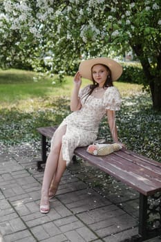 An attractive long-haired woman walks in the spring in the park of blooming apple trees. Spring portrait of a woman