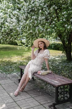 An attractive long-haired woman walks in the spring in the park of blooming apple trees. Spring portrait of a woman