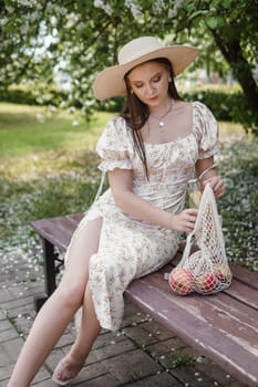 An attractive long-haired woman walks in the spring in the park of blooming apple trees. Spring portrait of a woman