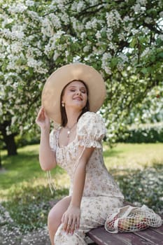 An attractive long-haired woman walks in the spring in the park of blooming apple trees. Spring portrait of a woman