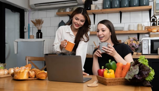 Female and female or LGBT couples are happily cooking bread together with happy smiling face in kitchen at home..