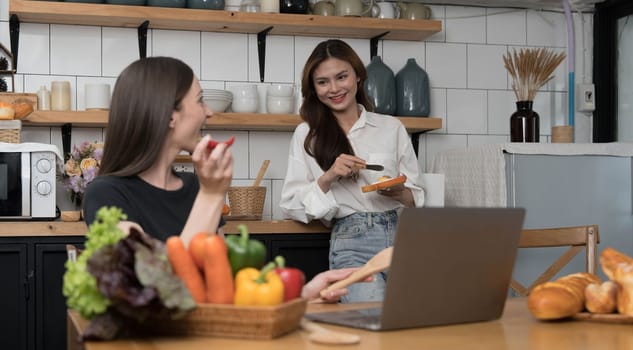 Female and female or LGBT couples are happily cooking bread together with happy smiling face in kitchen at home..