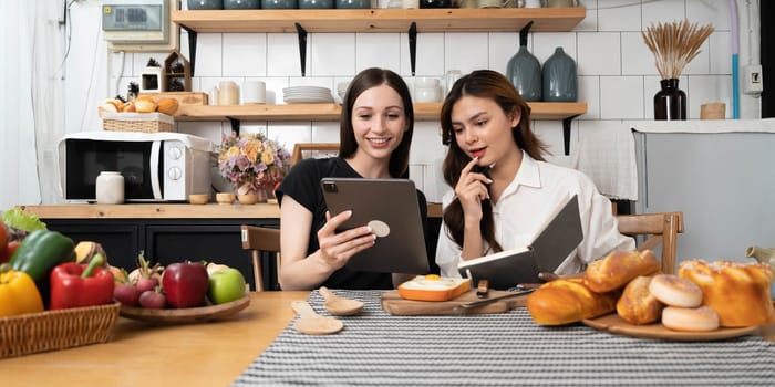 Female and female or LGBT couples are happily cooking bread together with happy smiling face in kitchen at home..